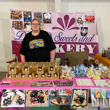 Woman selling assorted baked goods at a colorful bakery booth.