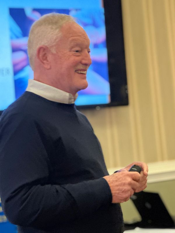 An elderly man smiling during a presentation.