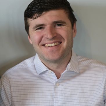 Smiling man in a light checkered shirt.