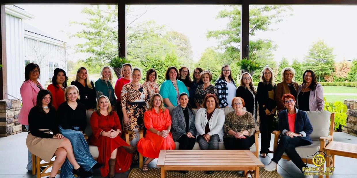 Large group of women posing together in an outdoor covered patio area.