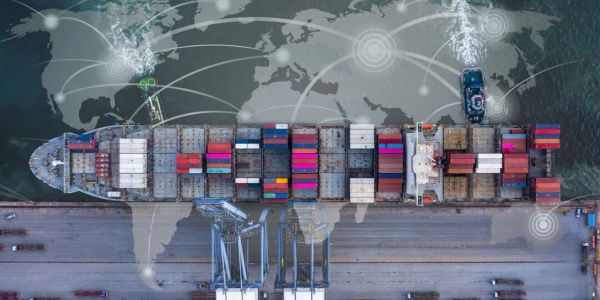 Aerial view of a cargo ship at a port with a world map overlay.