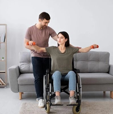 Therapist helping woman in wheelchair with arm exercises using small weights.