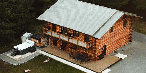 A cozy log cabin with a spacious wooden deck and outdoor amenities.