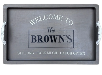 A wooden tray with handles featuring a welcoming family message.