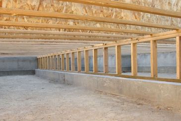Wooden framing and concrete foundation of a building under construction.