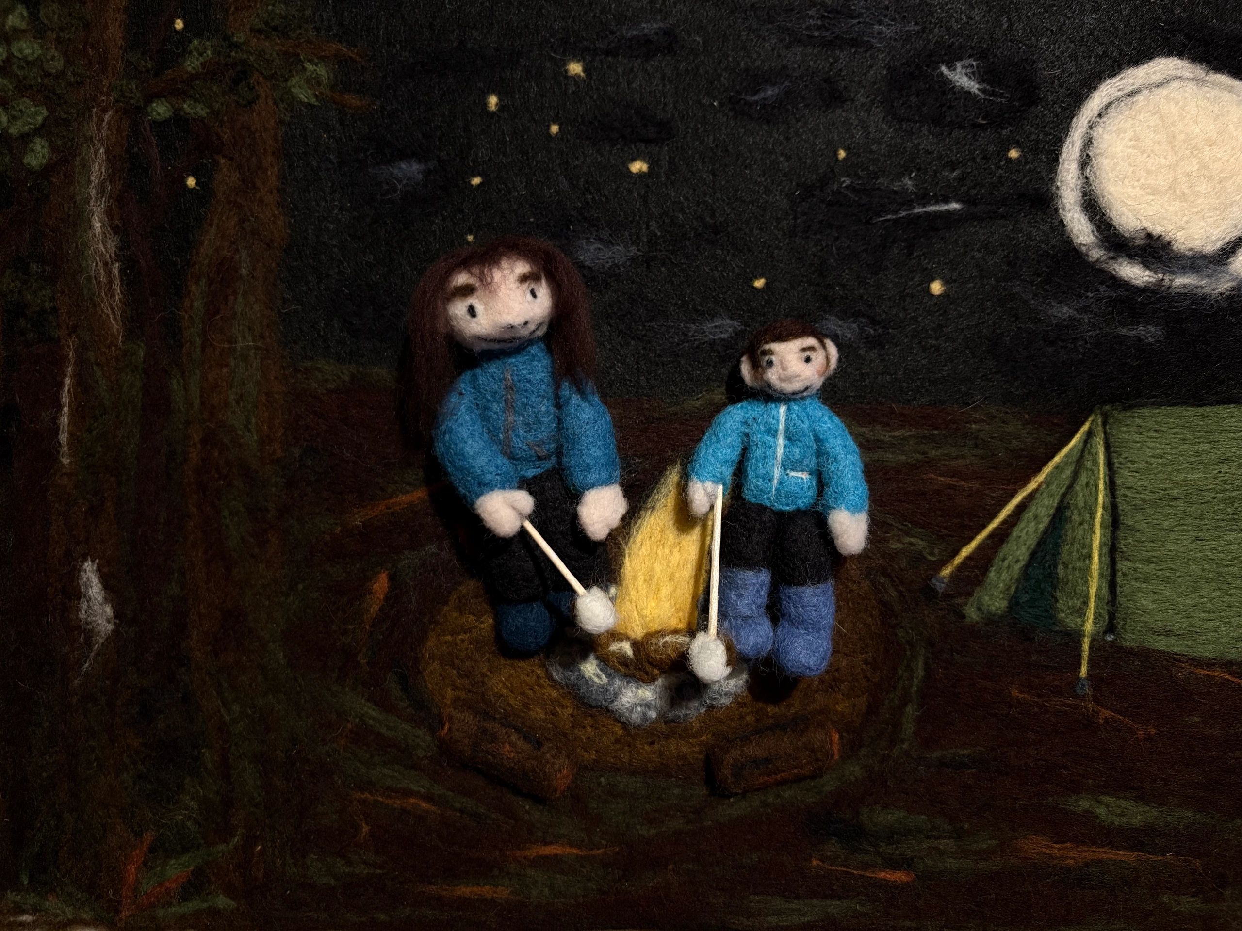 Woman and boy sitting around a fire in a starlit forest 