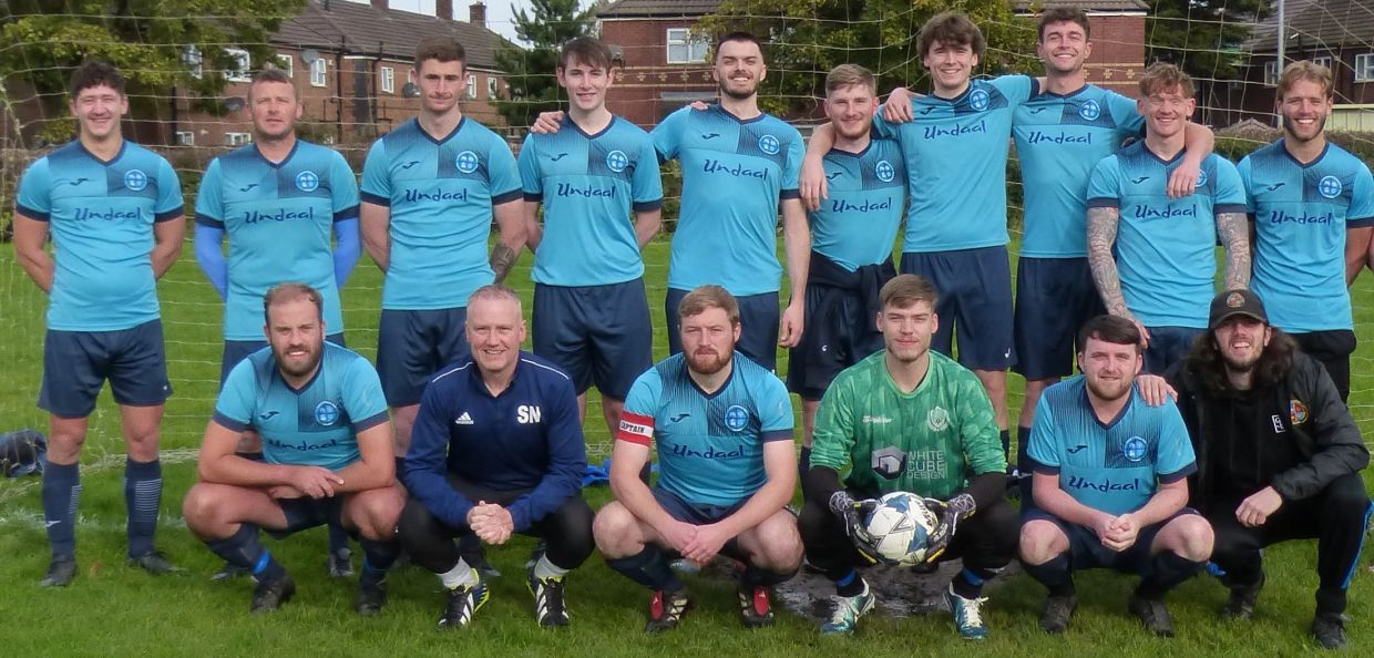 A local soccer team poses together before a match, wearing blue uniforms.