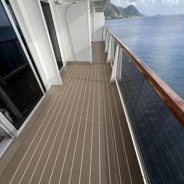 Balcony view from a ship overlooking calm ocean and distant mountains.