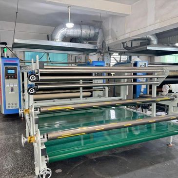 Industrial laminating machine with rollers in a factory setting.