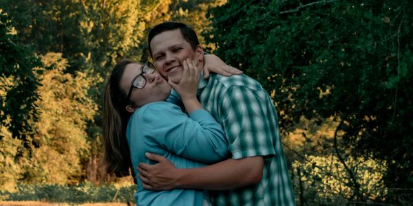 A couple embraces outdoors, sharing a joyful moment.