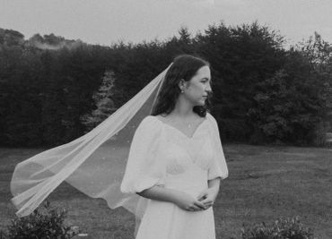 Black and white photo of a bride in a flowing veil outdoors.