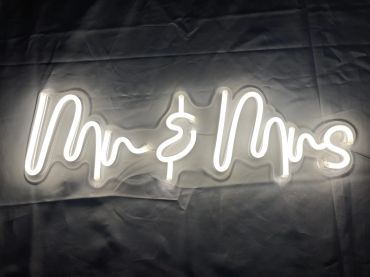 Illuminated neon sign reading 'Mr &amp; Mrs' on a dark surface.