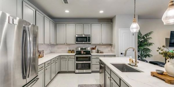 Modern kitchen with gray cabinets and stainless steel appliances.