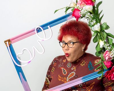 michelle pulling a face framed by a picture  frame with neon light saying love 