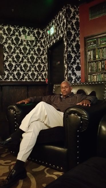 Man sitting confidently on a black leather armchair in a stylish interior.