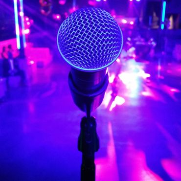 Close-up of a microphone on stage with vibrant purple and blue lighting.