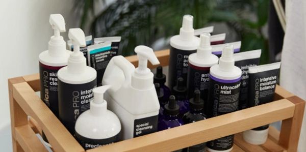 Wooden tray holding various skincare products with pumps and bottles.