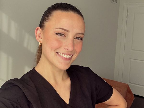 Young woman with a bright smile and winged eyeliner, wearing a black top.