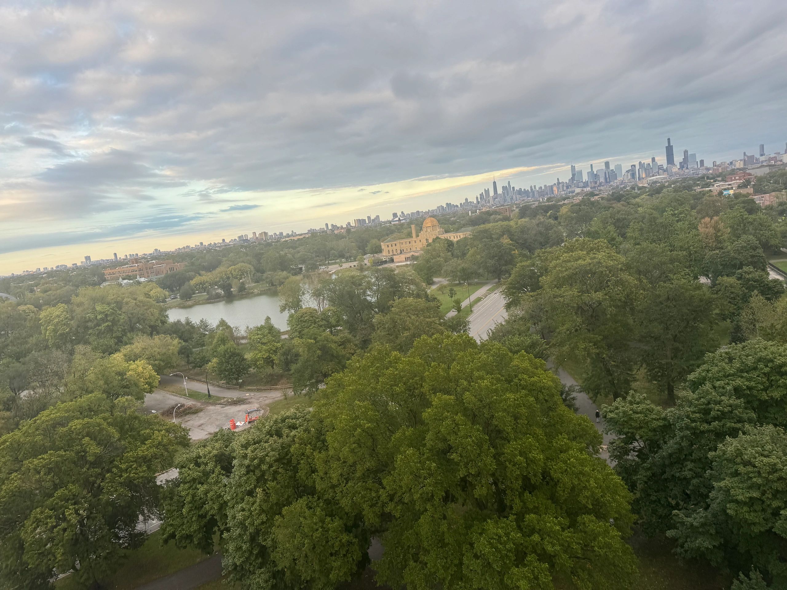 City skyline with park and cloudy sky.