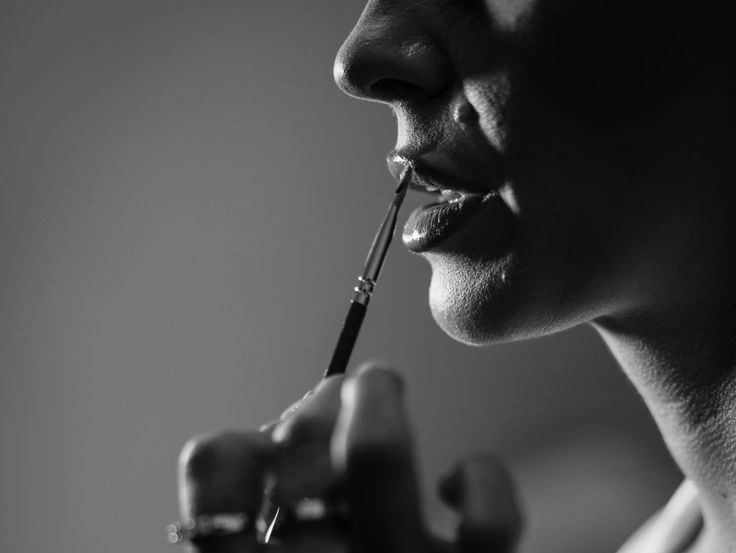 Close-up of a person applying lipstick with a brush.