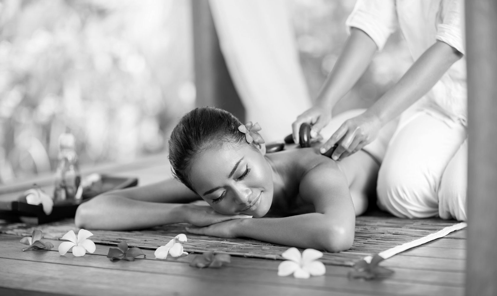 Woman enjoying a hot stone massage with flowers around.
