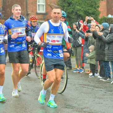 Runners and cyclists in a charity race with cheering crowd.