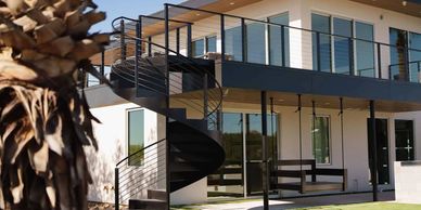 Modern house with a black spiral staircase and large glass windows.