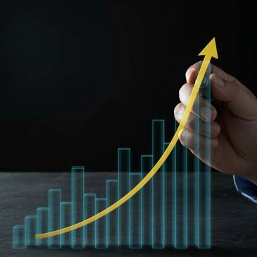 Hand drawing a rising yellow arrow over a blue bar chart, symbolizing growth.
