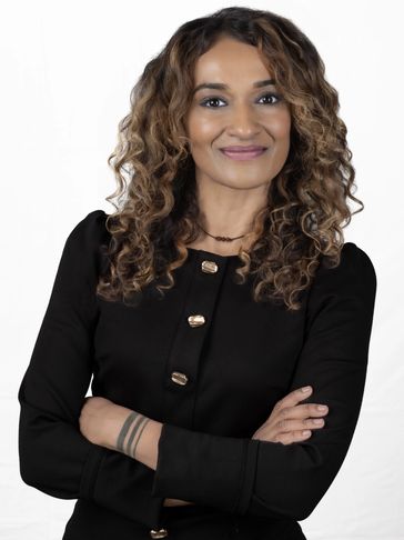 Confident woman with curly hair wearing a black outfit and smiling.