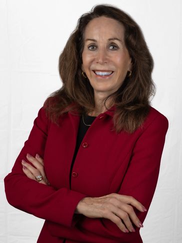 Confident woman in a red blazer smiling with arms crossed.