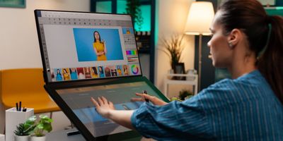 Designer editing photos and visuals on dual monitors, showcasing creative content production.