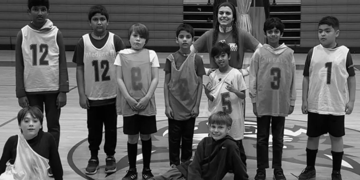 Youth basketball team posing with their coach in a gym.