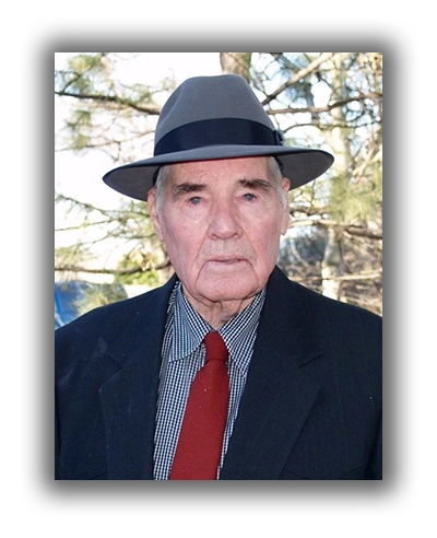 Elderly man wearing a gray fedora and formal attire outdoors.