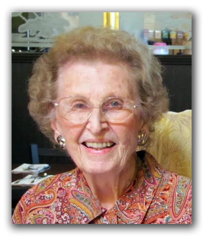 Smiling elderly woman wearing glasses and a colorful paisley blouse.
