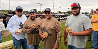 Four men holding awards outdoors.
