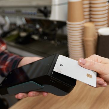 a hand holding a credit card terminal and another hand holding a credit card to make a payment