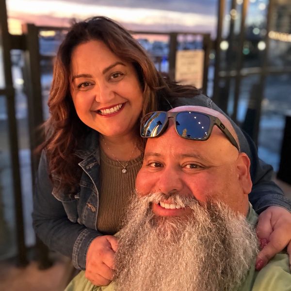 Couple smiling warmly with sunset background.