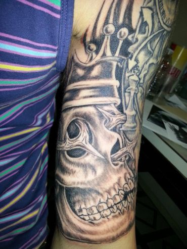Black and grey crowned skull on a sleeve tattoo.