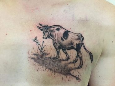 Black and grey Ferdinand the bull tattoo on a man's chest.