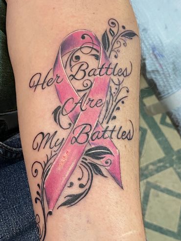 Cancer survivor pink ribbon tattoo with script lettering.
