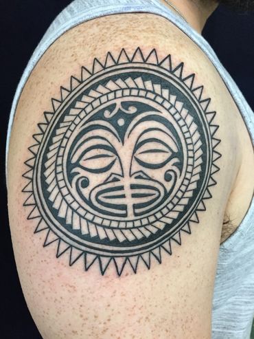 Tribal face tattoo on man's upper arm.