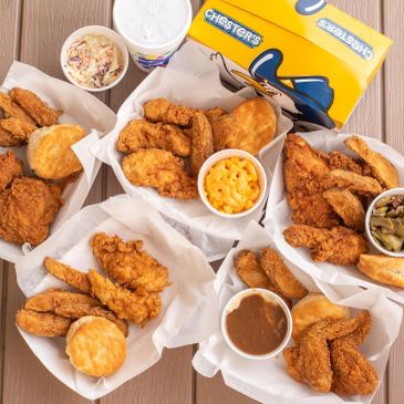 Multiple baskets of fried chicken meals with sides and biscuits.