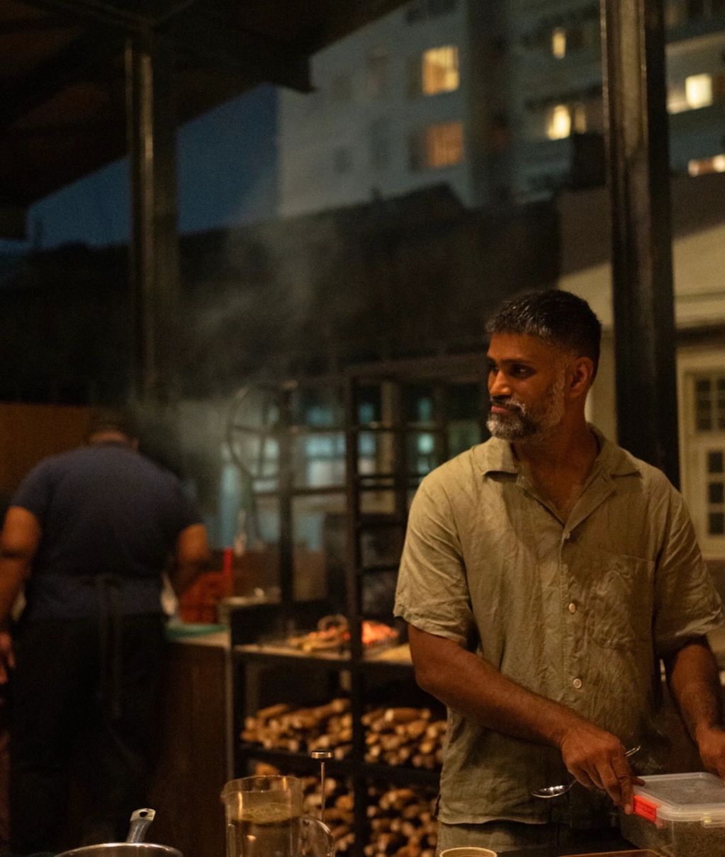 Man cooking outdoors at night by a grill.