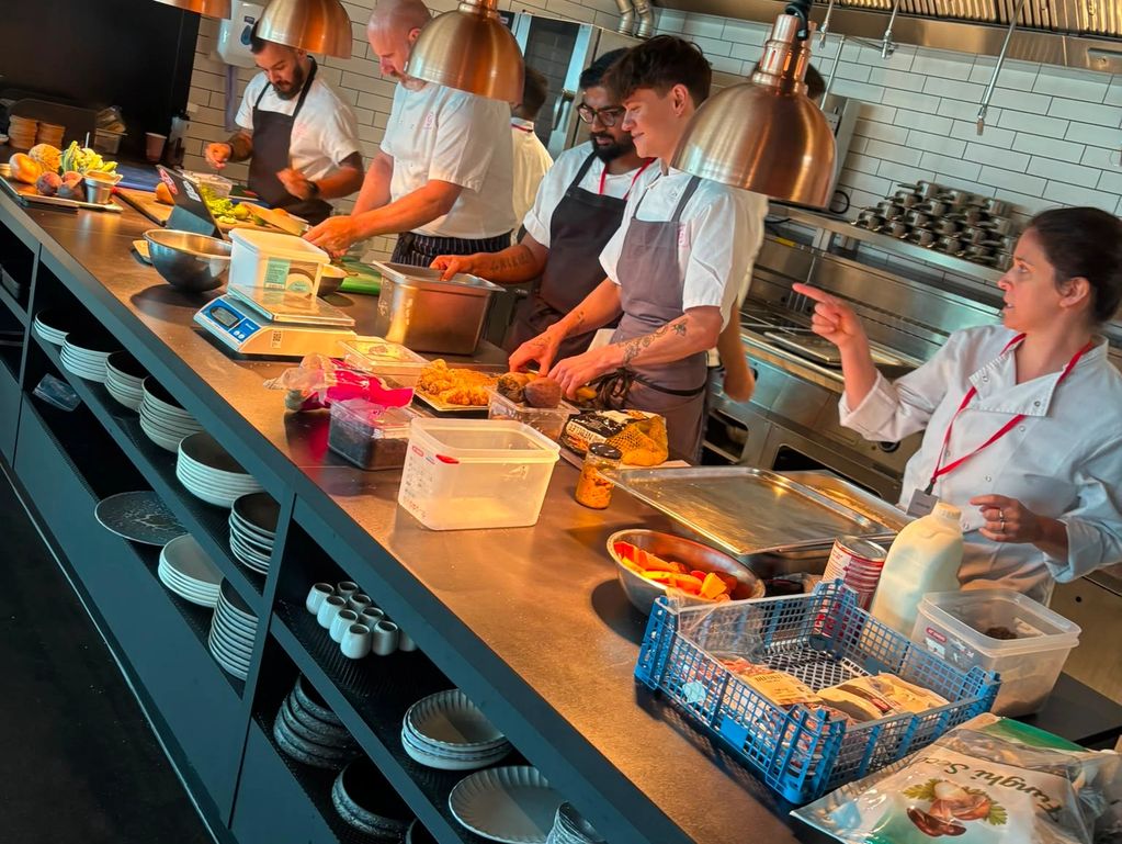 Chefs preparing food and working together in a busy kitchen.
