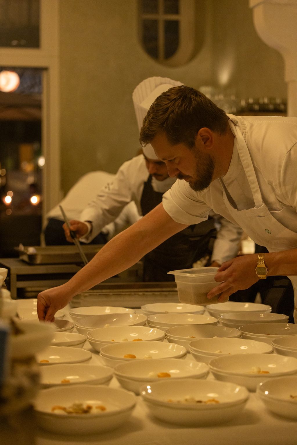 Chef preparing multiple dishes in a professional kitchen.
