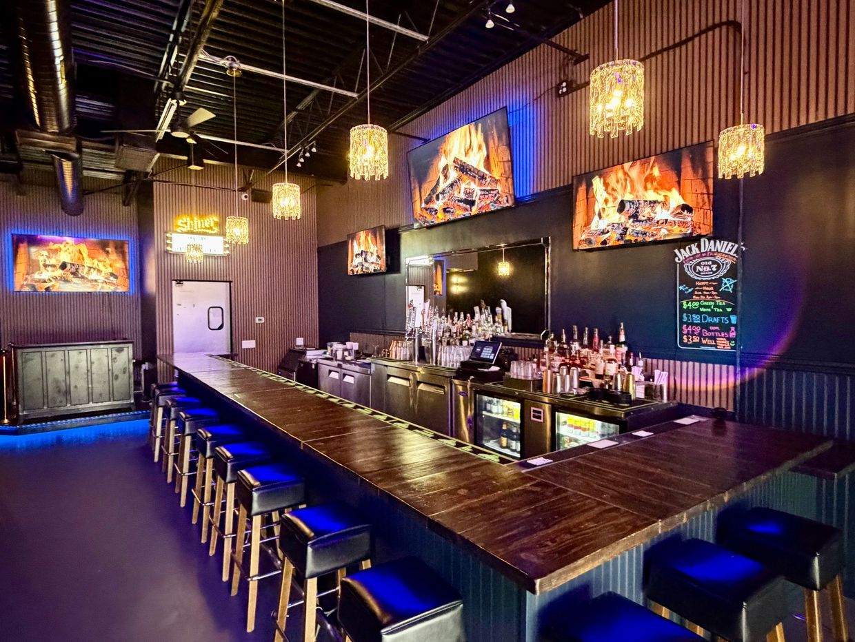 Modern bar with blue lighting and fireplace screens.