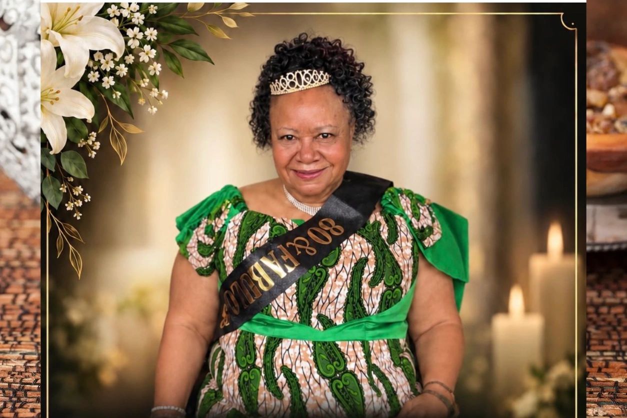 “Mrs. Harriet Tagoe smiling in a green patterned dress and headpiece.”