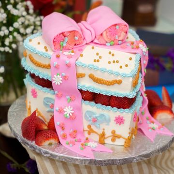 Decorative gift box cake with pink fondant bow and fresh strawberries.