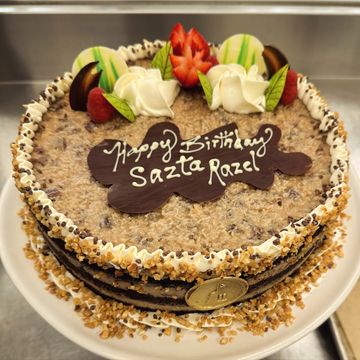 Decorated birthday cake with strawberries and chocolate writing.