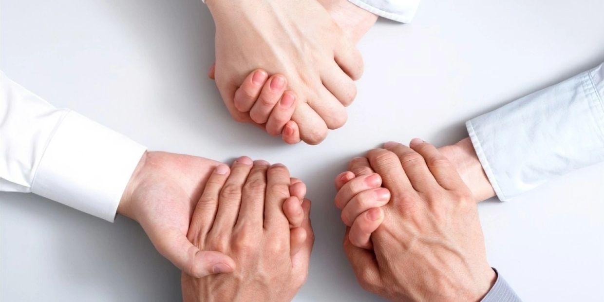 Three pairs of hands being held